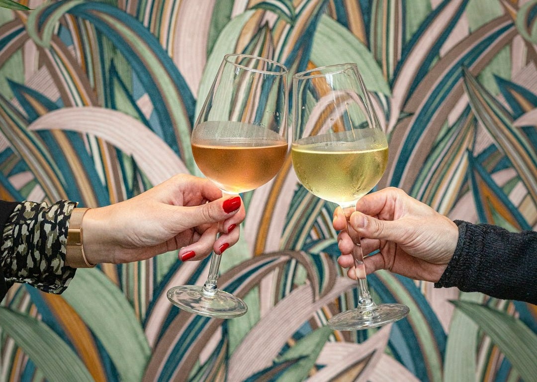 two people holding glasses of wine in front of a wallpaper