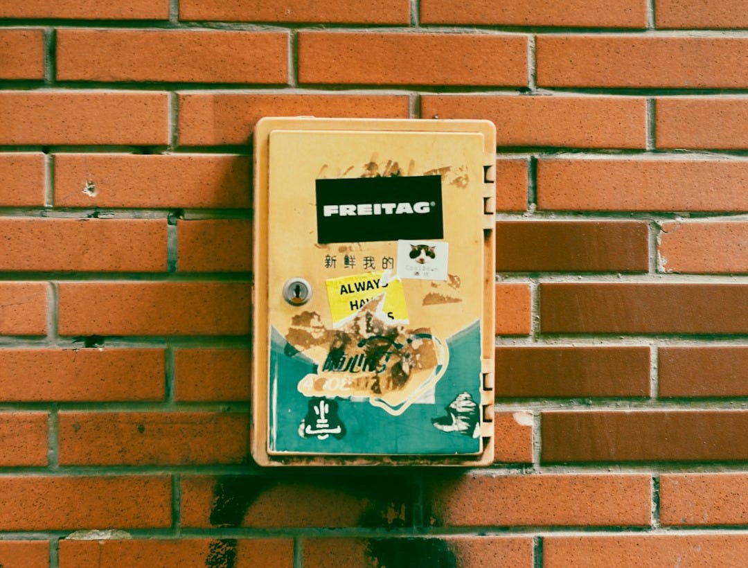 Yellow box with stickers on brick wall Yellow box with stickers on brick wall