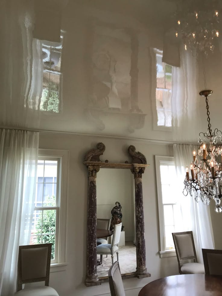 This may contain: a chandelier hanging from the ceiling in a dining room with two mirrors and chairs