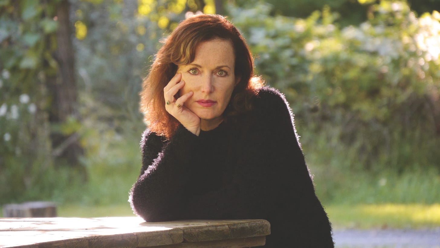 A woman stares into the camera with her head in her hand