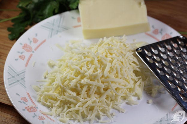 Grating the mozzarella cheese onto a plate Grating the mozzarella cheese onto a plate