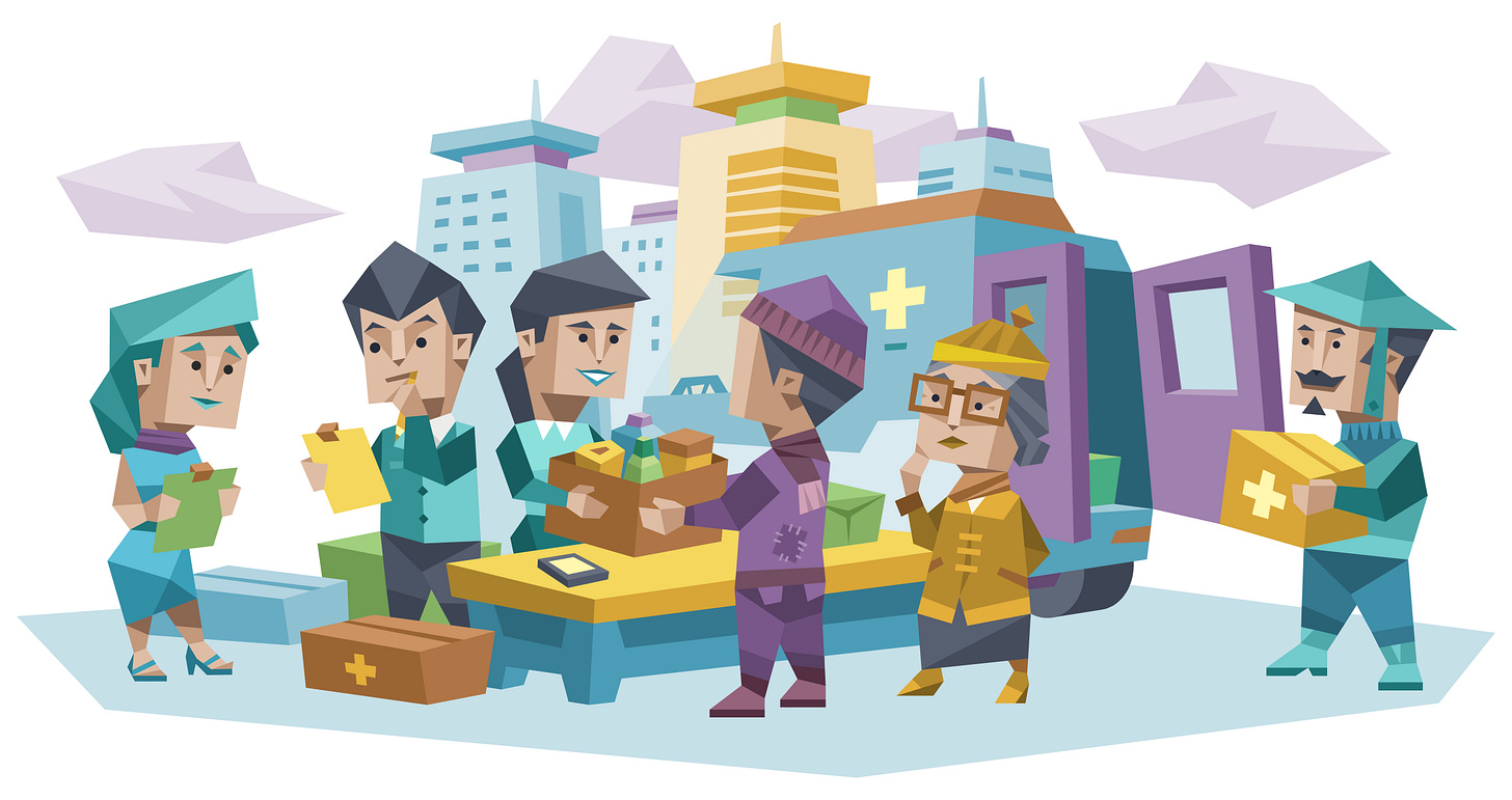 Six people gather around an ambulance outside a hospital. Three people stand in line to drop off supplies, while three others work at a table sorting paperwork and donated items.