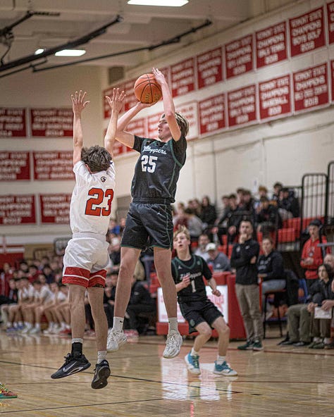 Five pictures of CVU boys basketball players in various stages of leaping and shooting with the ball. White uniforms with red lettering.