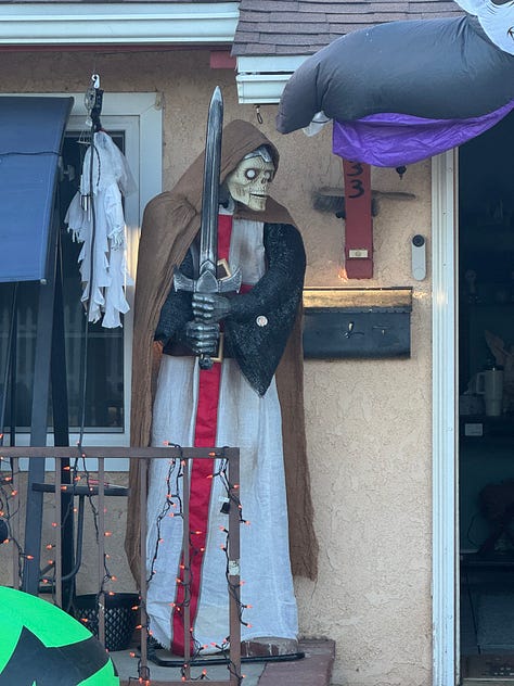 Various Halloween displays--including witches, skeletons, spiders, and a talking medieval knight--in front yards along Santa Paula Street.