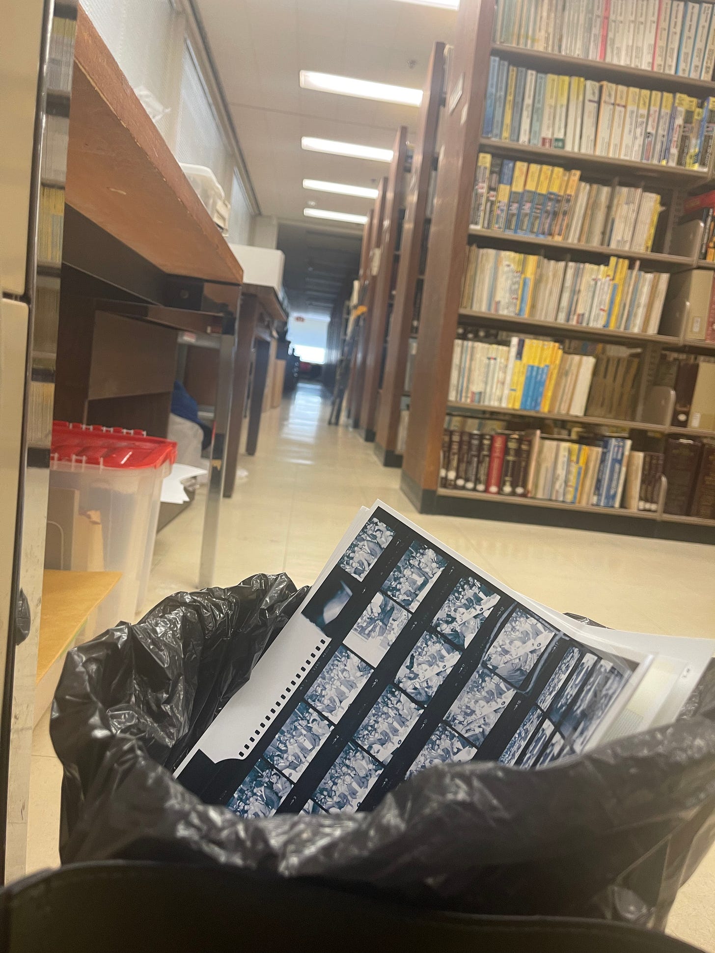 A pile of blue-toned photographic film negative contact sheets, each filled with multiple small images, sits inside a crinkled black plastic bag.