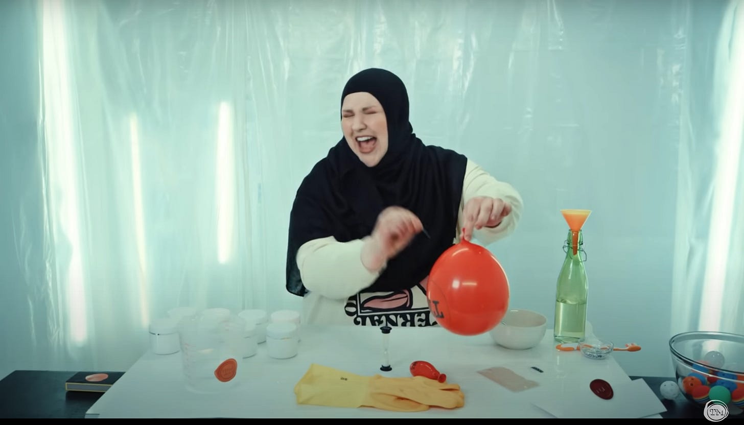 Fatiha El-Ghorri, in a long-sleeved T-shirt and black hajib, looks away as she prepares to pop a balloon with a straight pin.