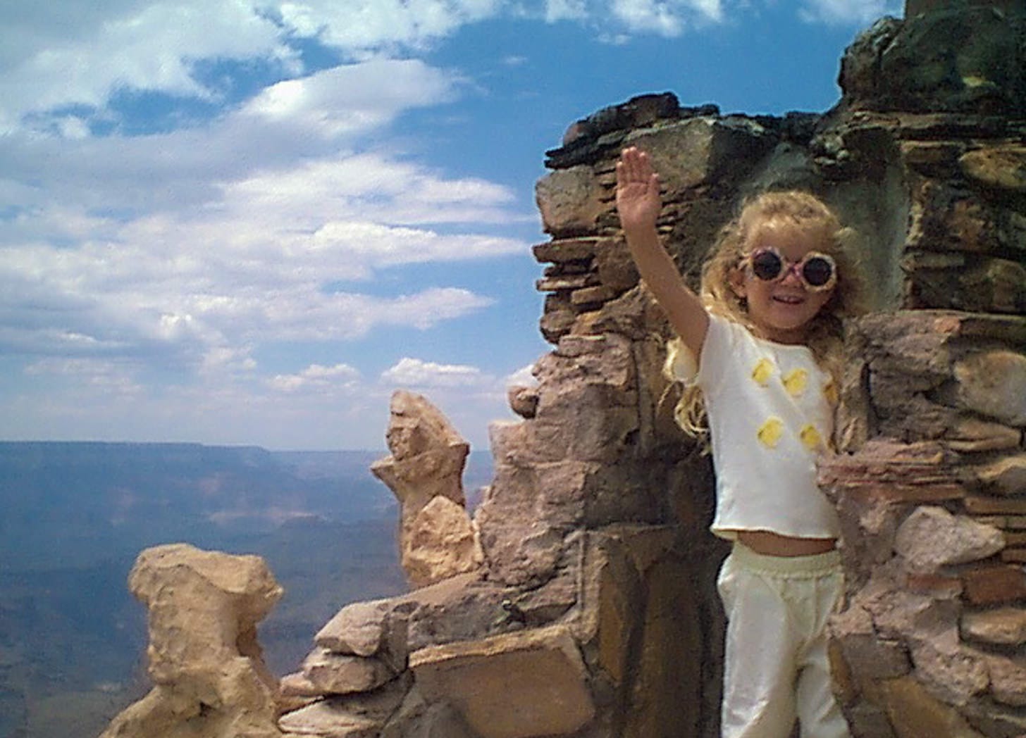 Little girl waving from an opening in a rock tower at the Grand Canyon