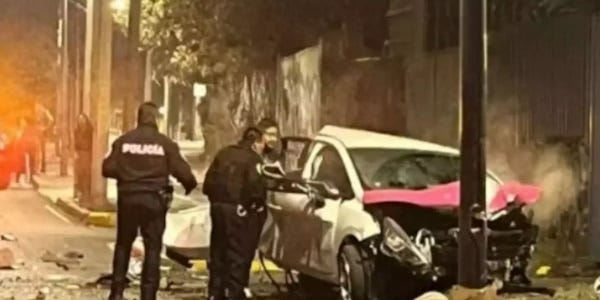 car crash scene photo taken at night shows a car wreck with police officers nearby and onlookers in the distance 