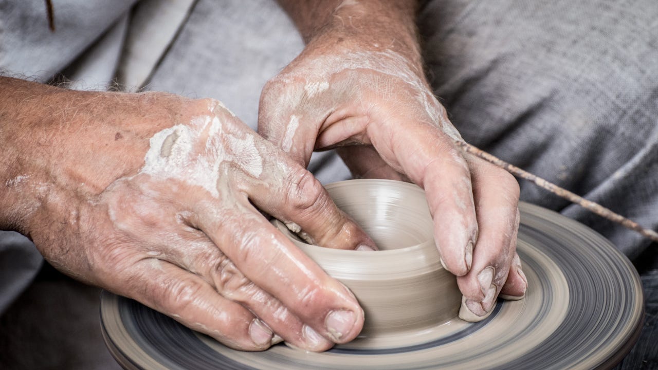 A potter molding a pot out of clay. A potter molding a pot out of clay.
