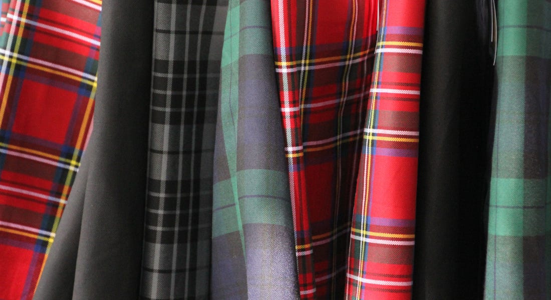 A row of tartan fabrics with red, black, and green folded materials