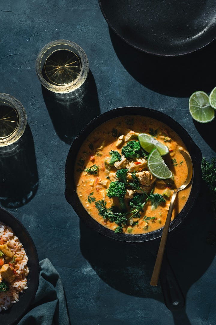 A bowl of curry, photo by Bruna Branco via unsplash. Coconut milk being poured onto the rice from the recipe above.