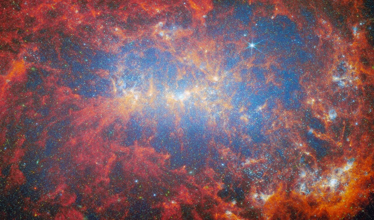 A close view of the central area of a dwarf galaxy. A huge number of stars fill the whole galaxy as tiny glowing points. They are brightest around the galaxy’s shining core. Thick clouds of gas and dust billow out across the scene, curling like moving flames. They glow in varying warm colors based on their location: orange around the galaxy’s core and around glowing star clusters in the bottom left, and dark red elsewhere. A close view of the central area of a dwarf galaxy. A huge number of stars fill the whole galaxy as tiny glowing points. They are brightest around the galaxy’s shining core. Thick clouds of gas and dust billow out across the scene, curling like moving flames. They glow in varying warm colors based on their location: orange around the galaxy’s core and around glowing star clusters in the bottom left, and dark red elsewhere.