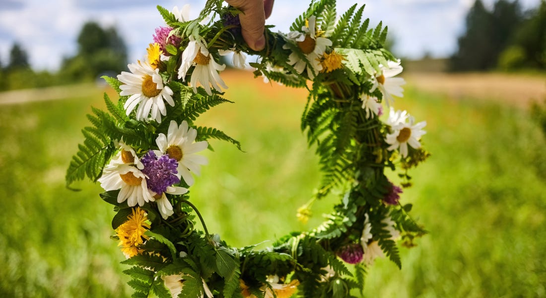 A wreath with daisies and purple flowers on it, with a lawn in the background A wreath with daisies and purple flowers on it, with a lawn in the background