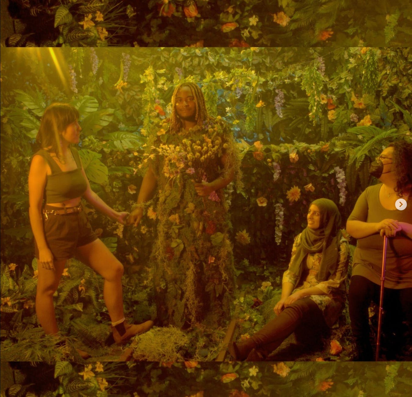 KB and friends in a floral background. KB is wearing a suit full of forest flowers.