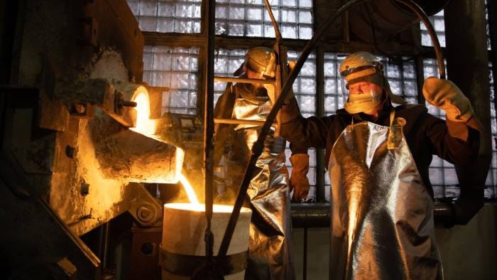 Workers fill a crucible with molten gold Workers fill a crucible with molten gold