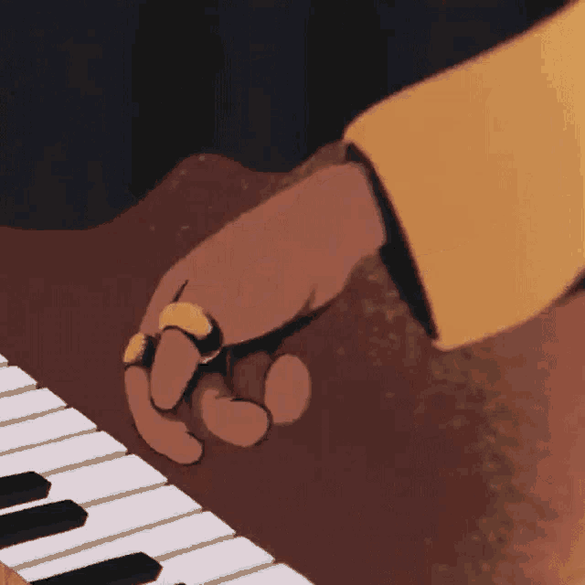 a person is playing a piano with a yellow ring on their finger .