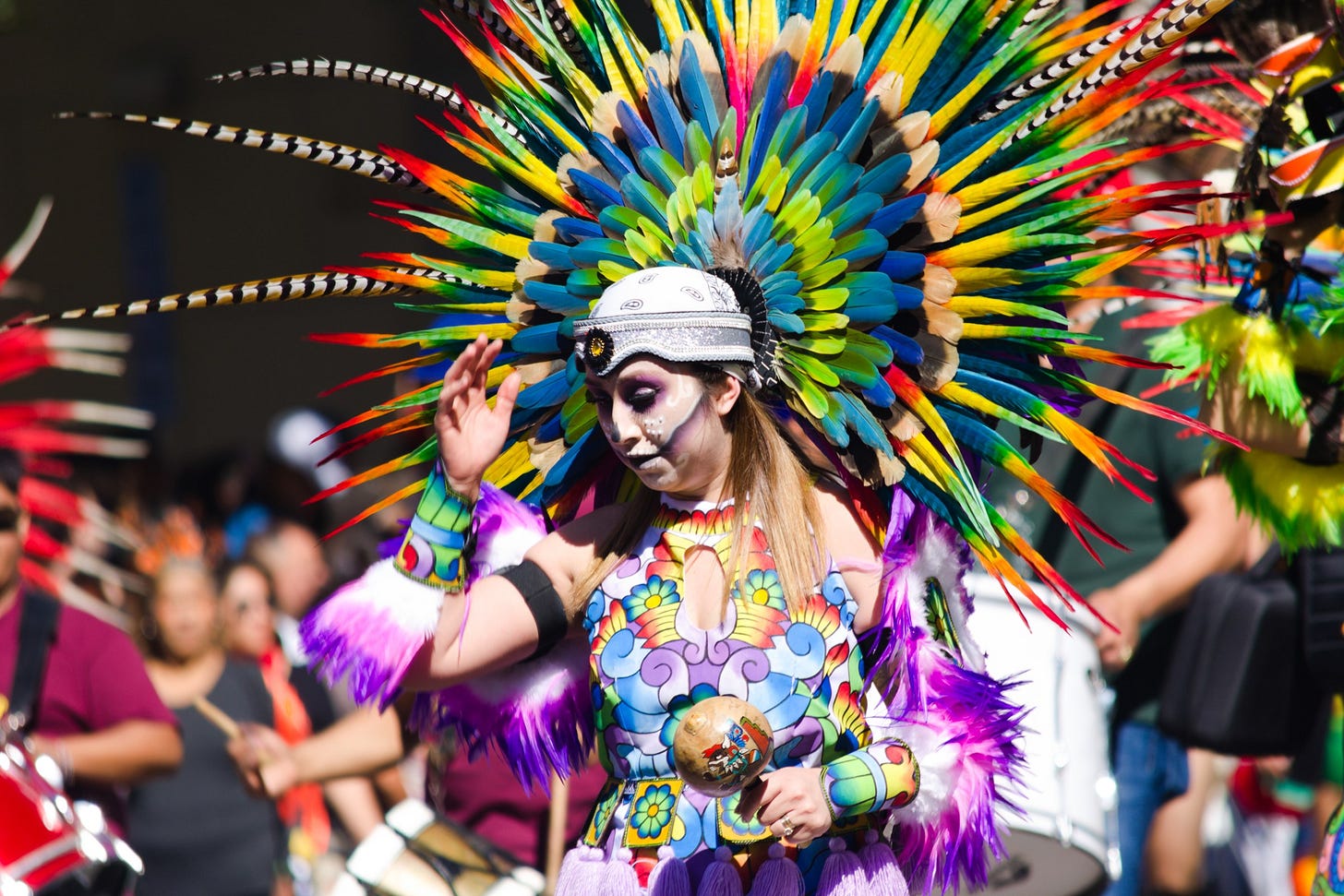 Dancer in a feathered headdress at the Viva la Vida Día de los Muertos parade in Austin
