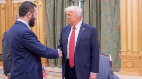 Two men shaking hands in a room

AI-generated content may be incorrect.
