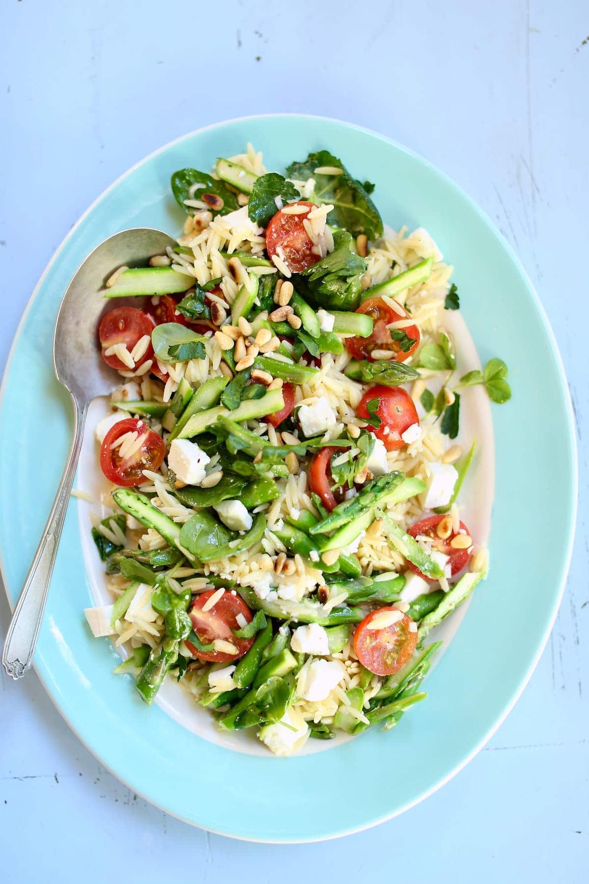a blue and white platter with pasta salad on it.