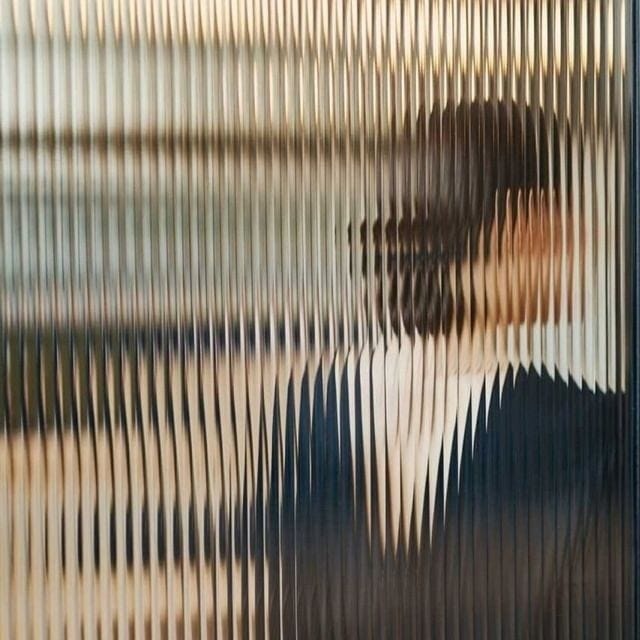 This may contain: a woman's face is seen through the blinds on a window sill in an office building