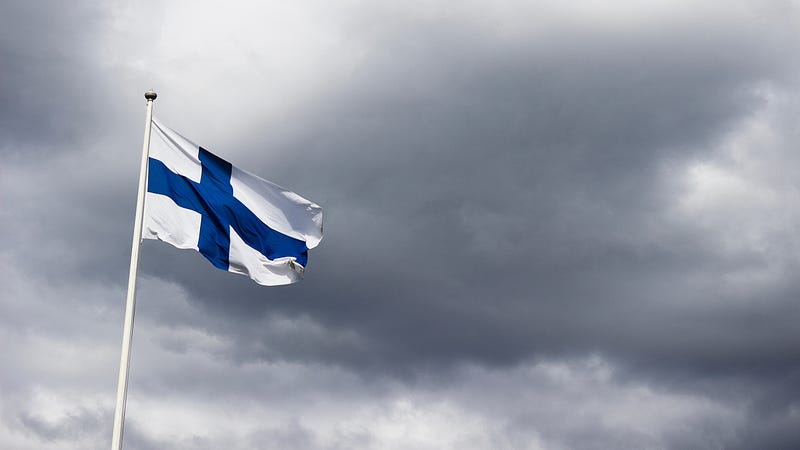 The Finnish flag in white and blue against a grey sky