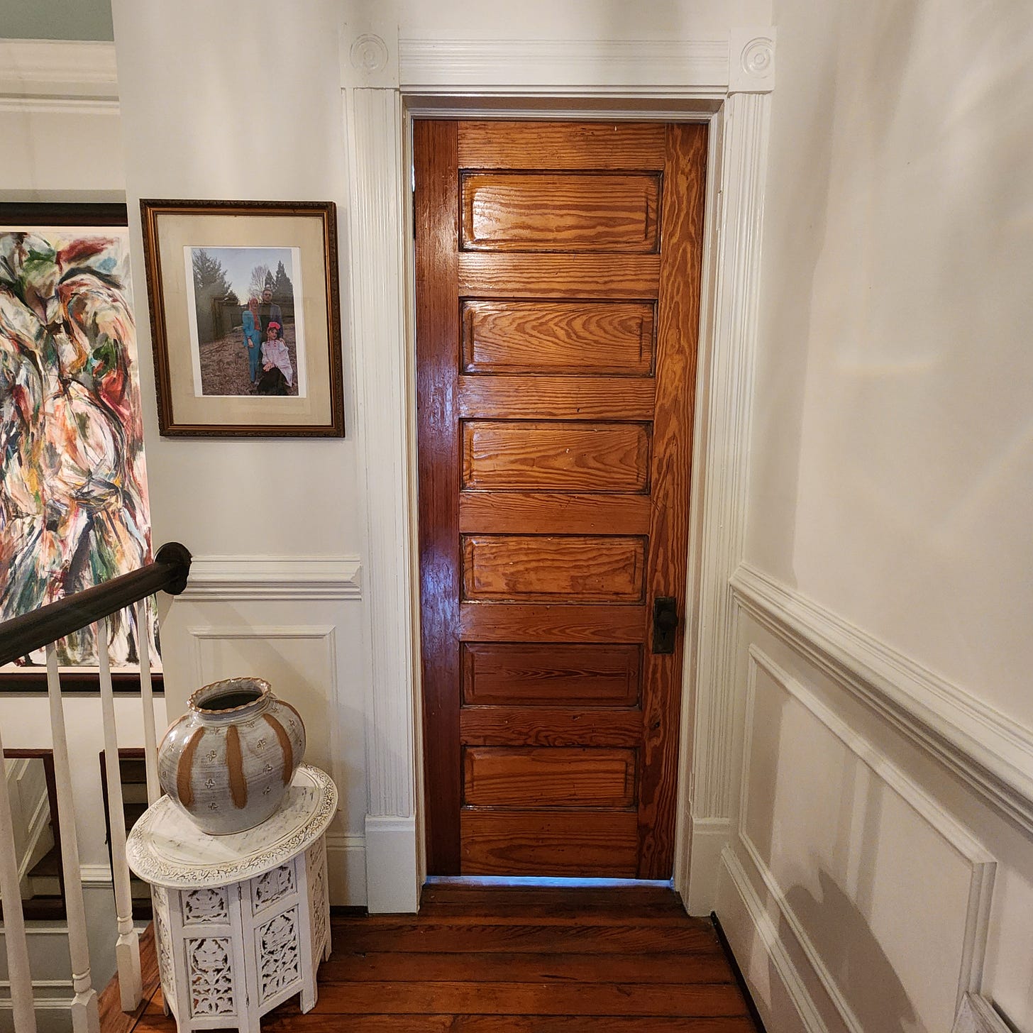 Picture of a heart pine six panel door in a white hallway in an old Victorian house. 