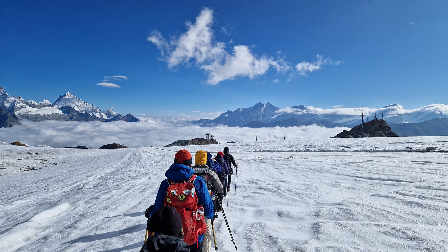 Hikers roped together walking along a glacier. Blue sky and spiky mountains on horizon. Hikers roped together walking along a glacier. Blue sky and spiky mountains on horizon.