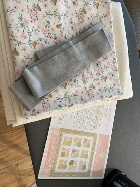 Spring blossoms out the windows, the fabric for the quilt, my sewing machine and the ranunculus in a vase.