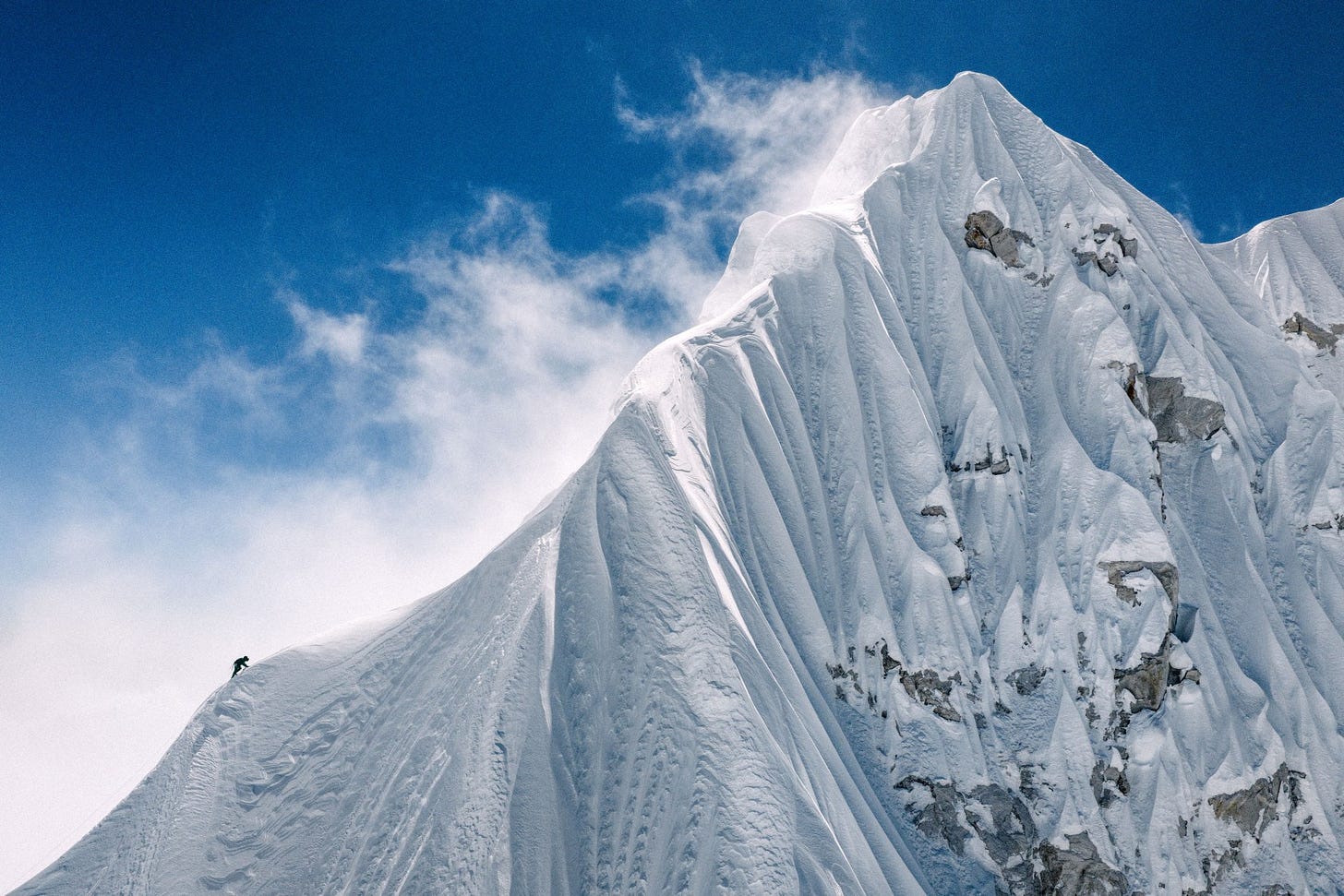 A lone French mountaineer traversing a snow-covered ridge near the summit of Jannu East in eastern Nepal.