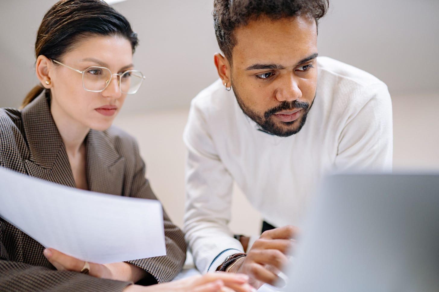 Two professionals look at a computer screen.