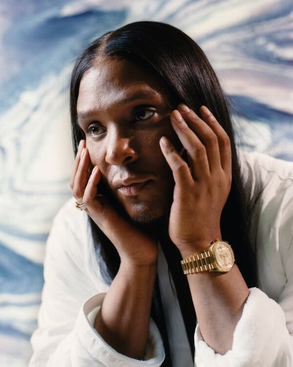 Law Roach, cupping his face in his hands and wearing a large gold watch on his left wrist.