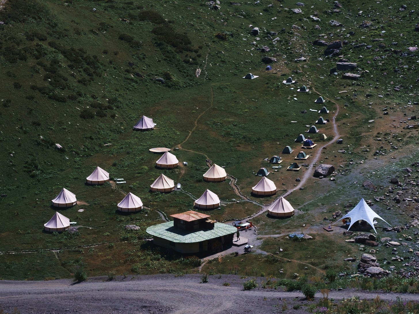 An overhead view of a collection of tents and a small building. 