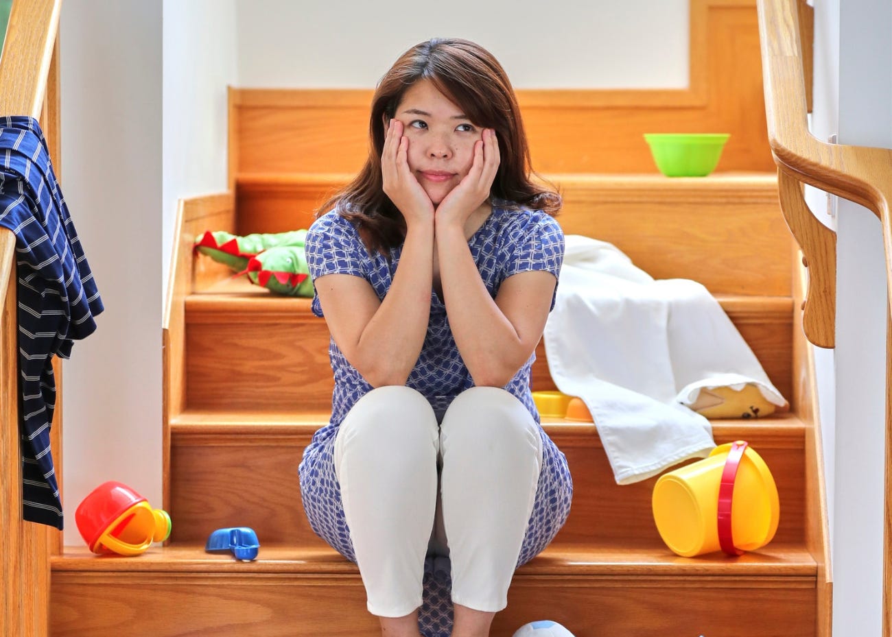 parent sitting on stairs with toys strewn about