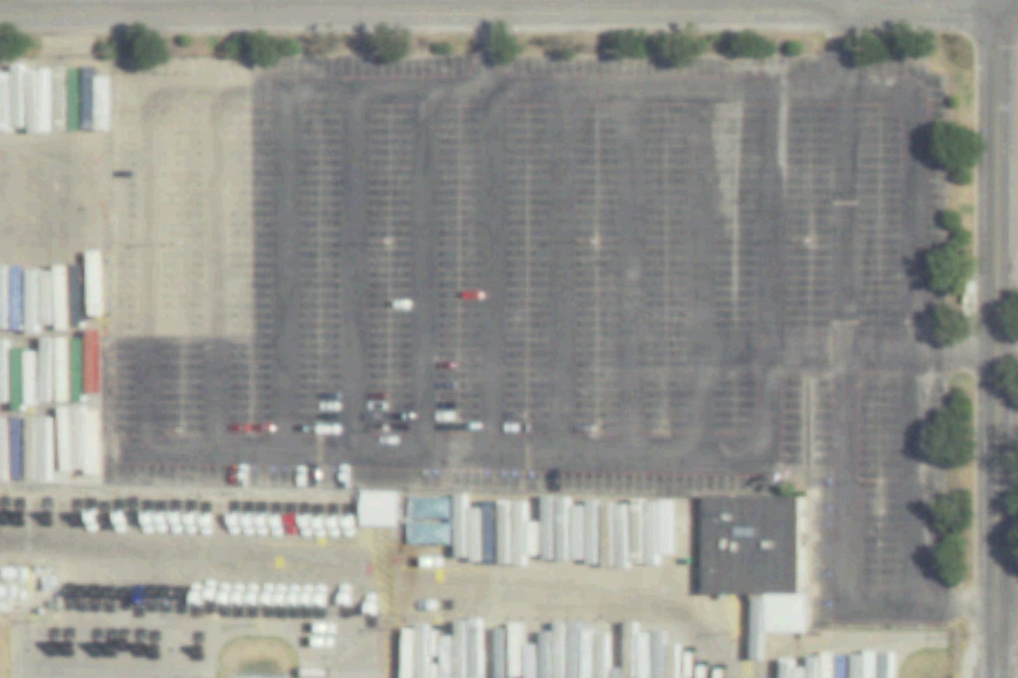 A real Dallas lot, straight from free 15cm public imagery — dark surface, faded striping, aging sealcoat. You can read the neglect from a plane.
