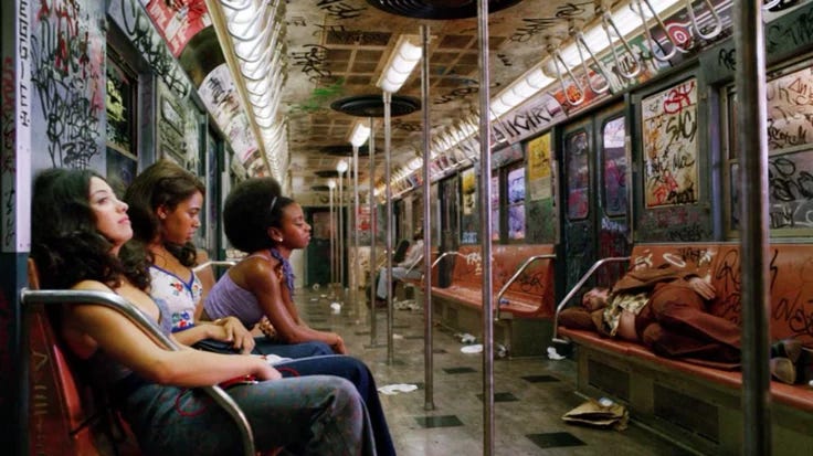 This may contain: three women sitting on a subway car with graffiti all over the walls