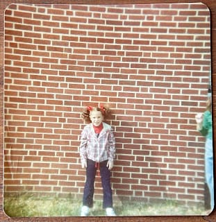 Me, at 8 years old, with pigtails, standing in front of a brick wall at recess. Me, at 8 years old, with pigtails, standing in front of a brick wall at recess.
