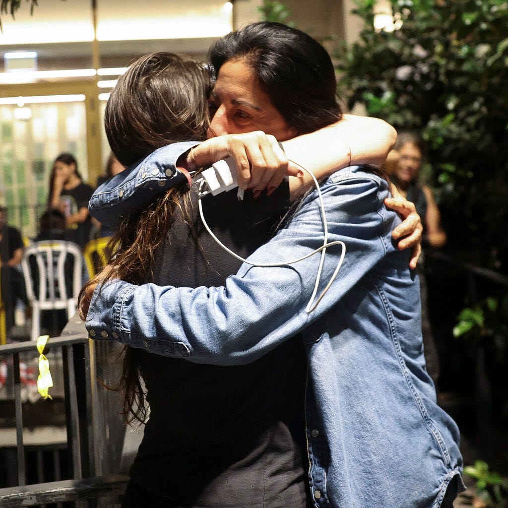 Two women embrace.