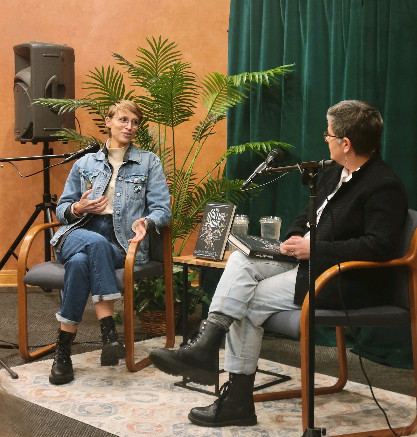 Susan chatting with Megan Whalen Turner on a stage with microphones and their books Susan chatting with Megan Whalen Turner on a stage with microphones and their books