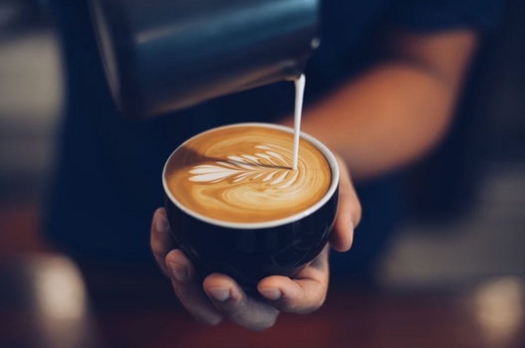 Barista pouring steamed milk into a specialty coffee Barista pouring steamed milk into a specialty coffee
