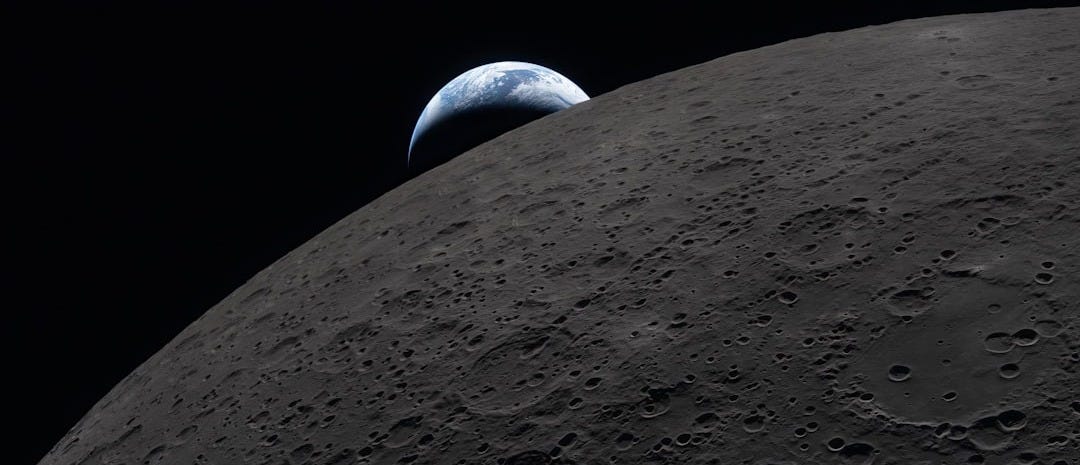 Earth rises over the dark lunar surface