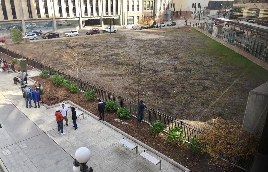 A bare-looking transit stop next to an empty lot in a downtown area.