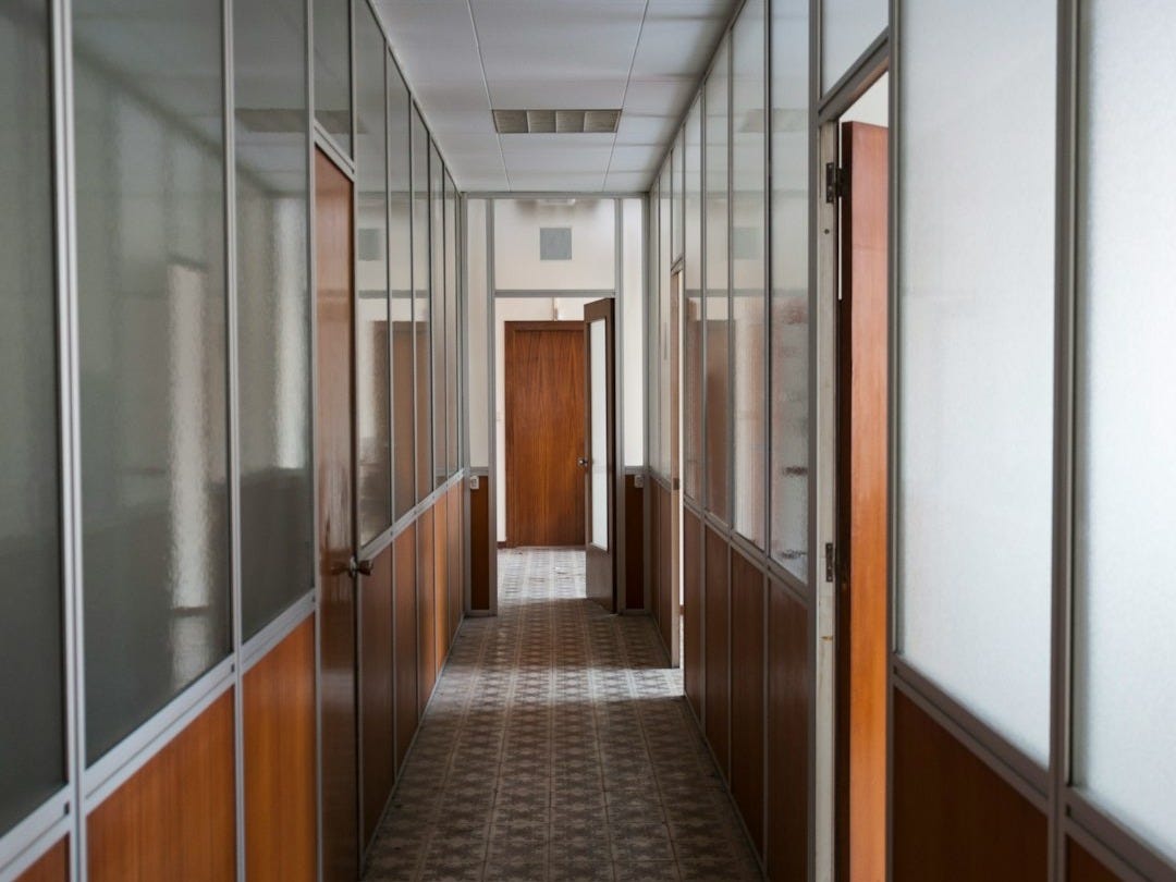 a long hallway with a tiled floor and wooden doors