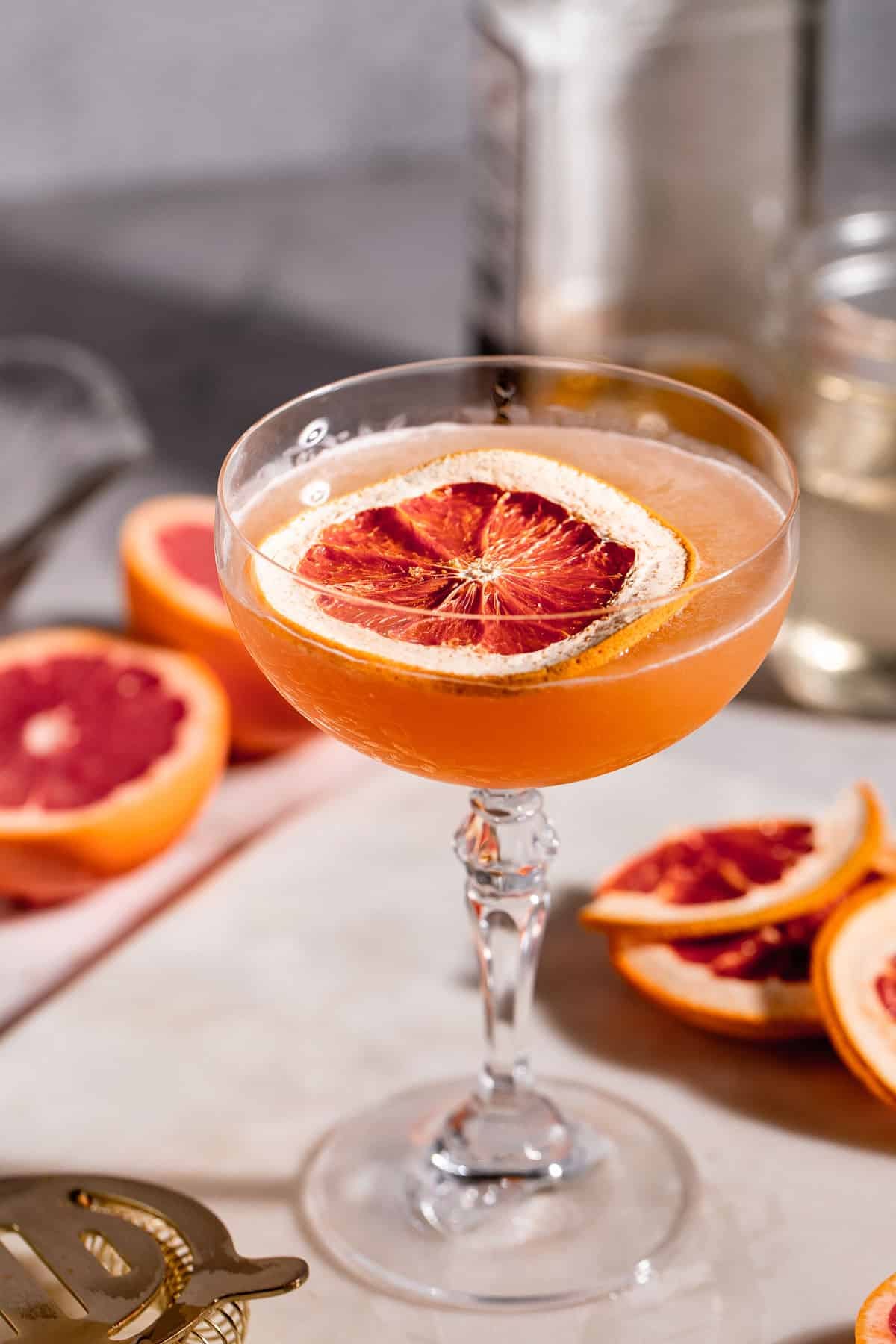A Brown Derby Cocktail served in a stemmed glass garnished with a slice of grapefruit.