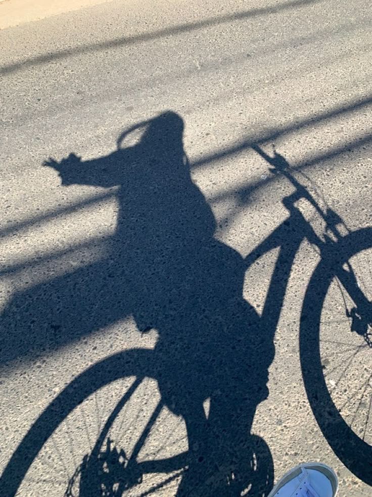 This may contain: a shadow of a person riding a bike on the street