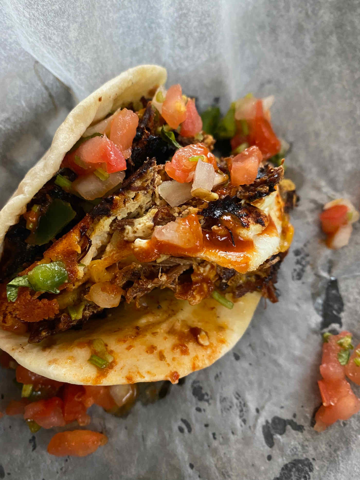 Tortilla overflowing with carnitas, egg, and pico de gallo