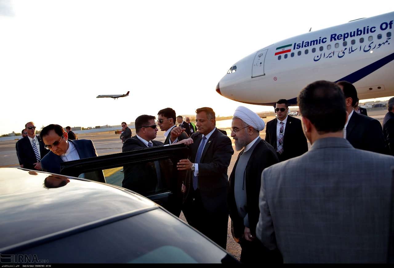 Hassan Rouhani beside a black car, surrounded by US Secret Service agents on the tarmac at JFK, with an Iranian government aircraft behind them.