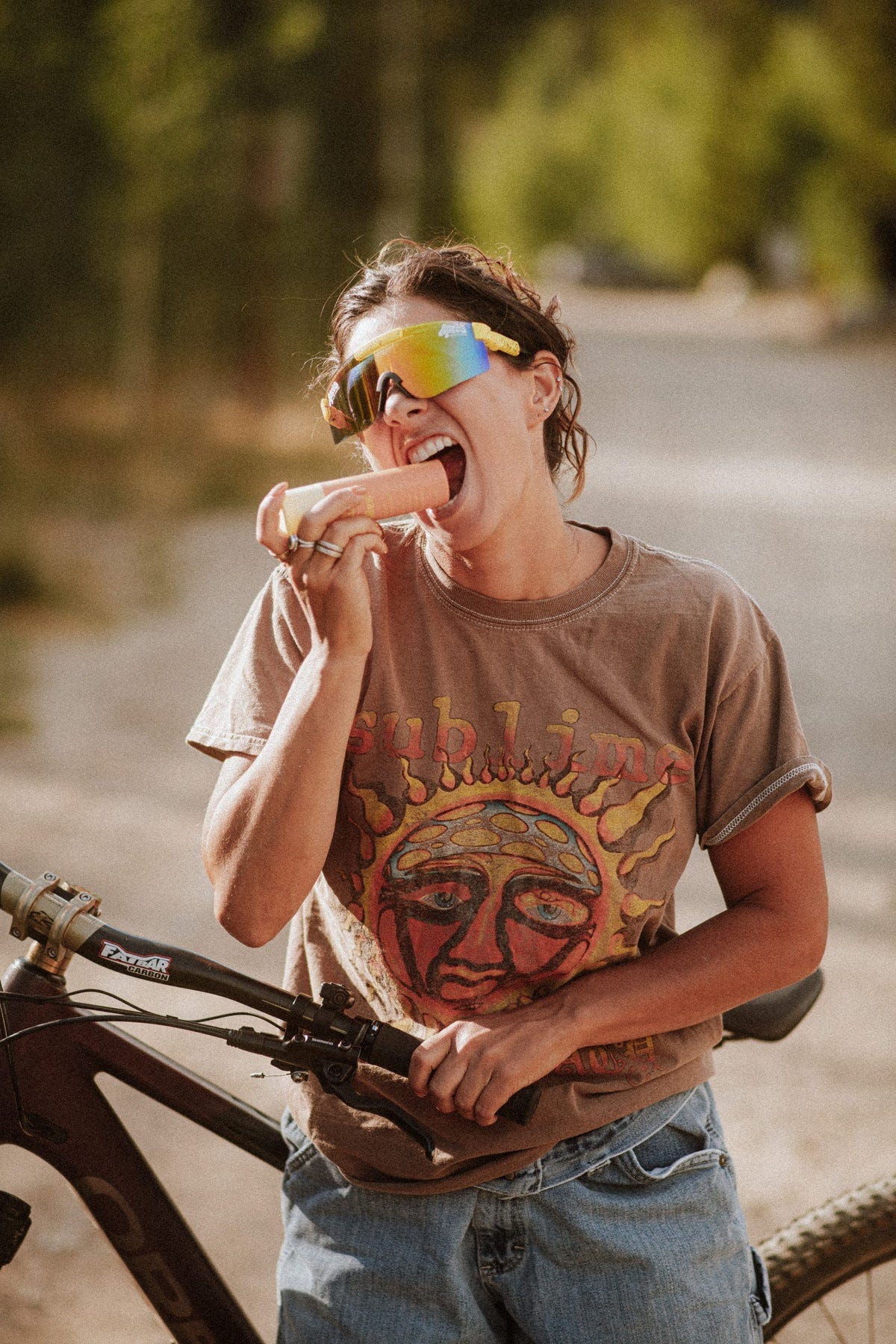 Kaitlyn, Swellies founder, taking a bite of a Swellies bottle mid ride