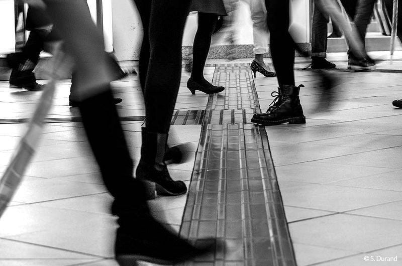 May be a black-and-white image of one or more people, turnstile and street