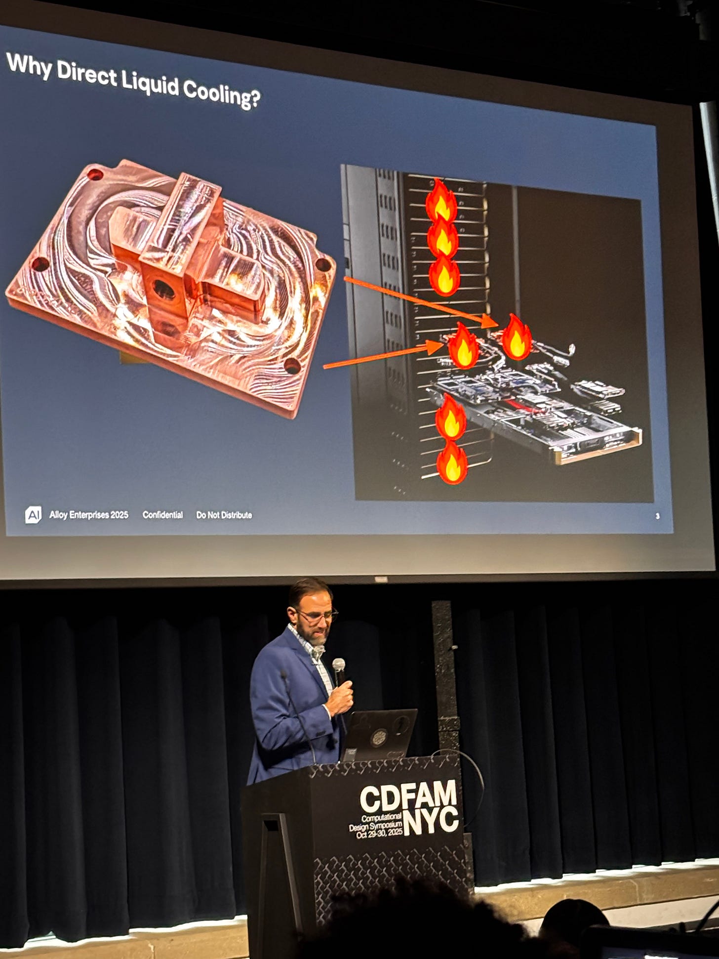 Ryan Ohara of Alloy Enterprises speaking at CDFAM NYC 2025 about direct liquid cooling, with a close-up image of a cooling plate on the left and a computer setup with flames indicating overheating on the right.