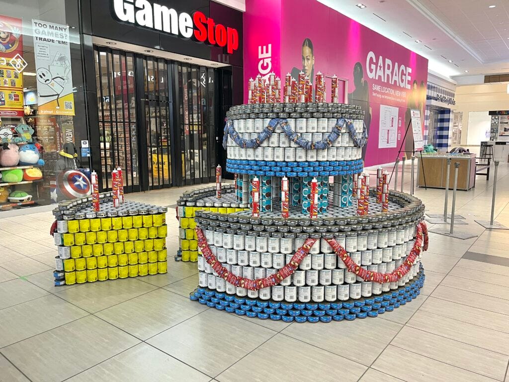 Canstruction submission. Canned food arranged to look like a very large cake with a slice taken out of it.